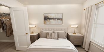 A bedroom with a large bed, two lamps, and a painting on the wall.